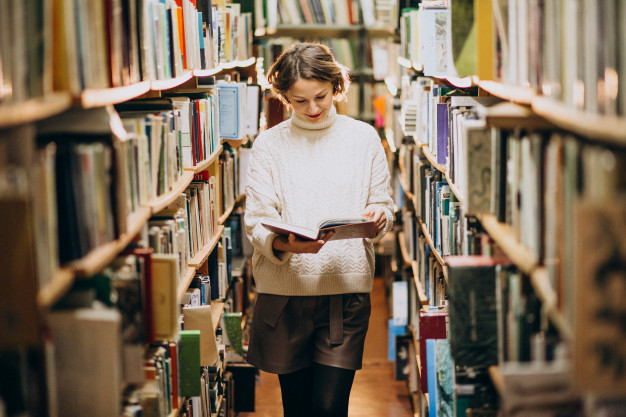 mulher lendo livro em biblioteca